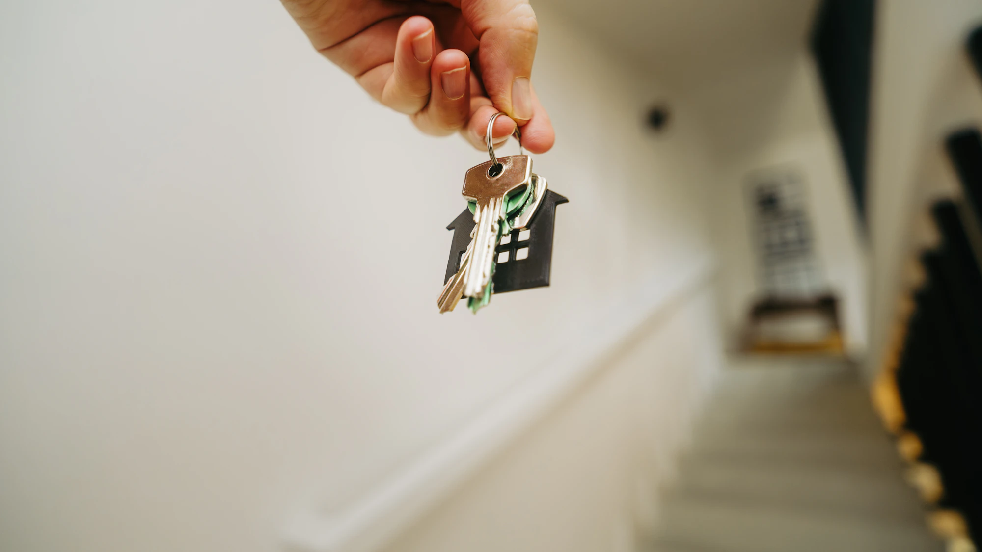 A close-up of a person holding a single house key between their fingers